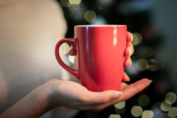 Mains tenant une tasse rouge brillante, parfaite pour la collection de tasses thermoréactives festives