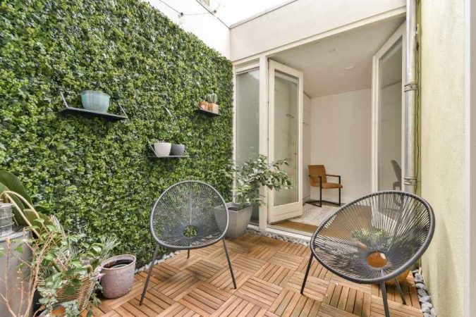 Terrasse avec mur végétal, dalles en bois et chaises design, une idée originale pour créer un jardin intérieur urbain et élégant.